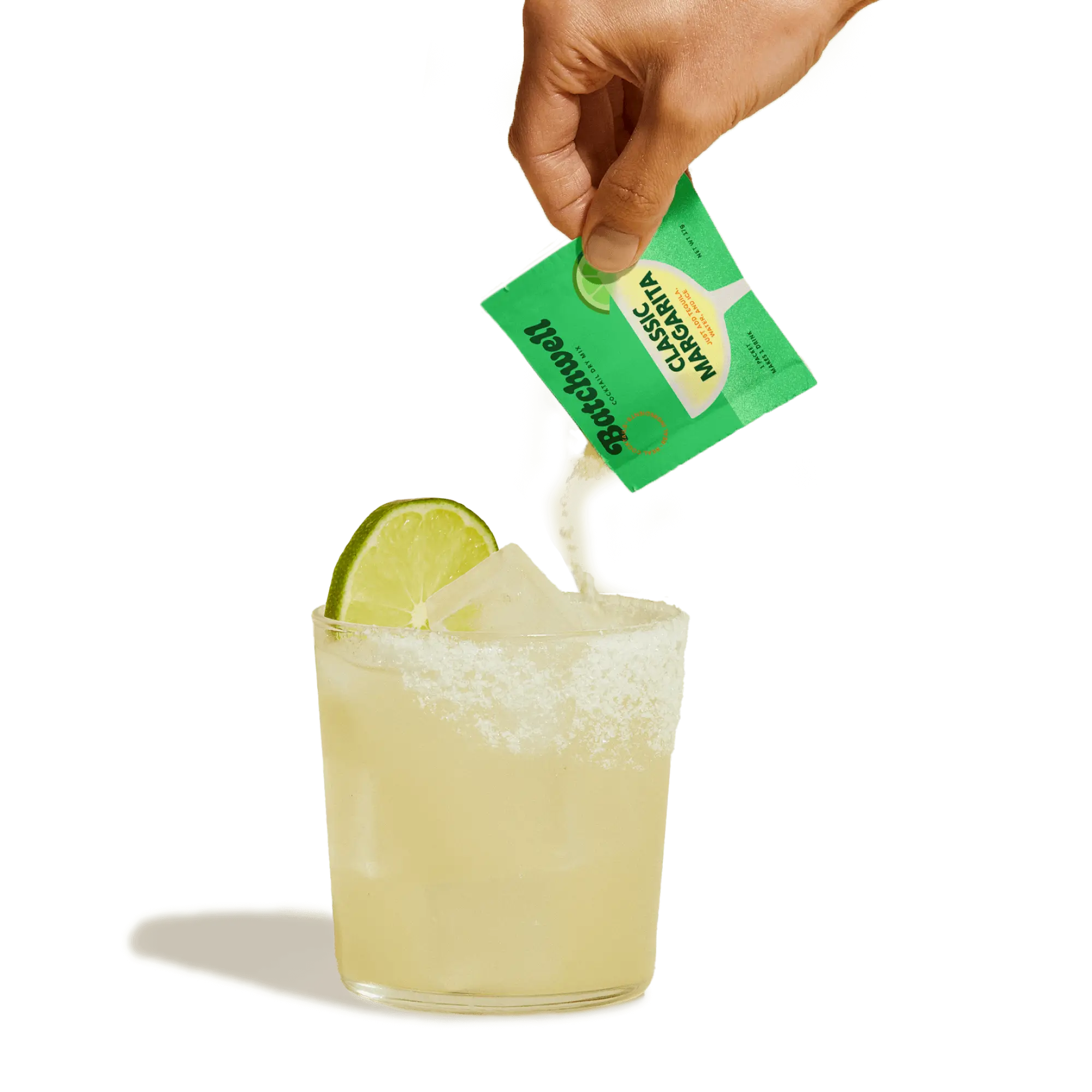 hand pouring a classic margarita sachet into a glass with ice, a salted rim, and a lime on top