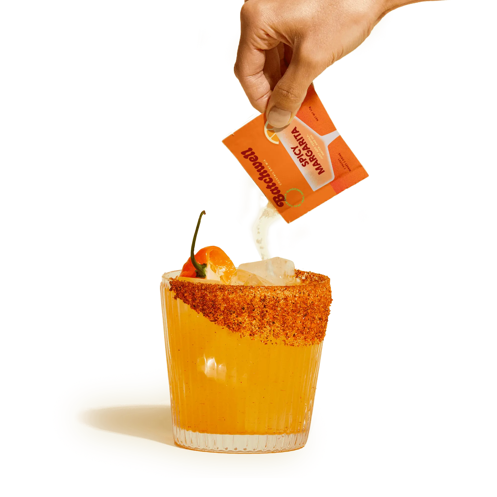 hand pouring a spicy margarita sachet into a glass with ice, a salted rim, and a jalapeño on top